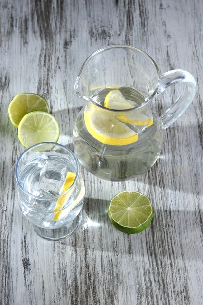 Glass pitcher of water and glass on wooden table closeup