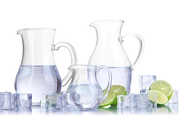 Photo glass pitchers of water with ice and lime isolated on white