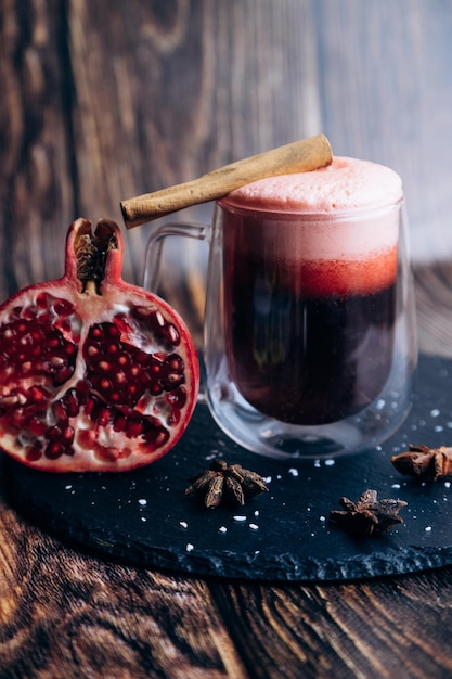 A glass of pomegranate juice next to a pomegranate.