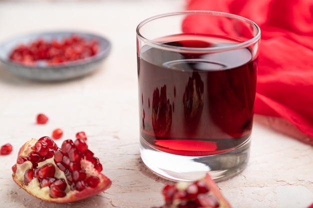 Glass of pomegranate juice on a white concrete background