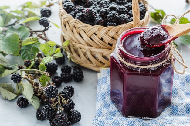 Glass pot of blackberry jam, basket filled with blackberries, blackberry bunch,