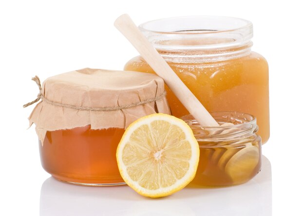 Glass pot full of honey and lemon isolated on white