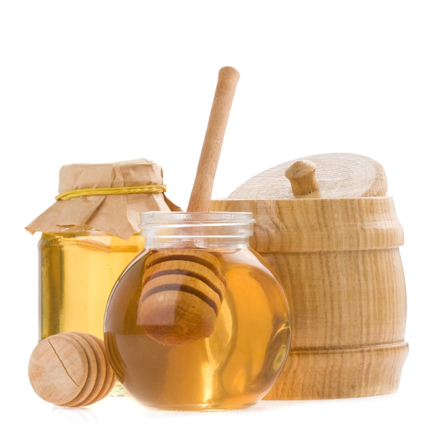 Glass pot of honey and stick isolated on white