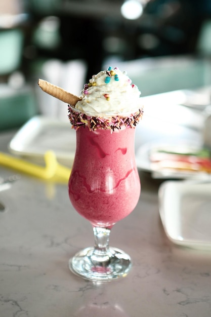 Glass of raspberry milkshake with whipped cream and fresh raspberries