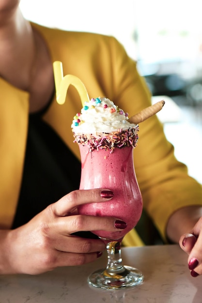 Glass of raspberry milkshake with whipped cream and fresh raspberries