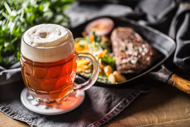 Bicchiere di birra rossa in pub o ristorante sul tavolo con cibo delizioso.