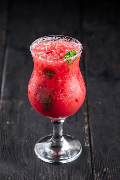 Glass of red berry cocktail on wooden background