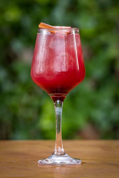 Glass of a red cocktail on a wooden table