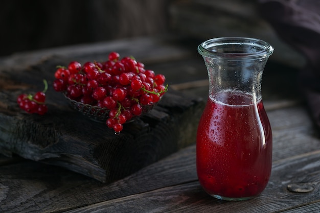 Glass of red currant cocktail or mocktail, refreshing summer drink with crushed ice and sparkling water on a dark wooden