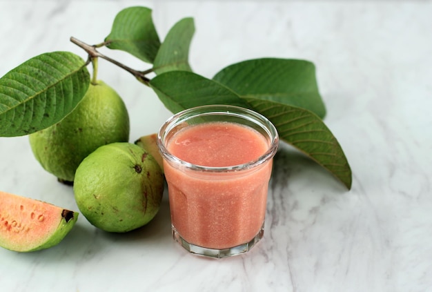 A Glass Red Guava Juice on Wooden Background with Guava Fruit slices and Leaf Copy Space for Text