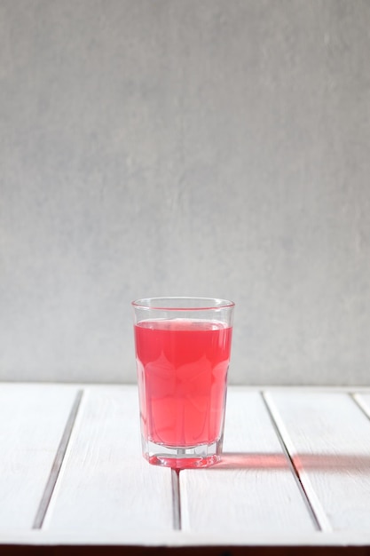 A glass of red liquid with a red drink in it.