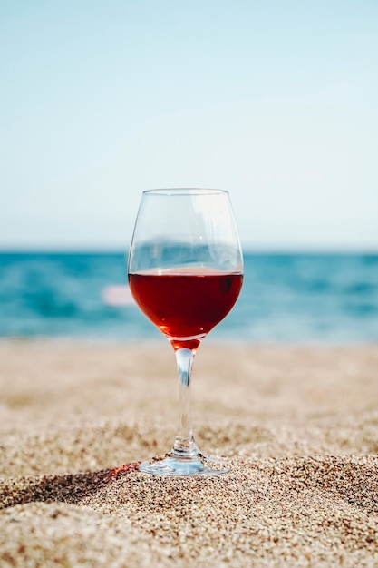 Glass of red wine against the background of the mediterranean beach and the sea in a tourist town in...