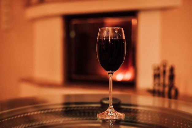 A glass of red wine on a glass table near the fireplace Christmas Eve