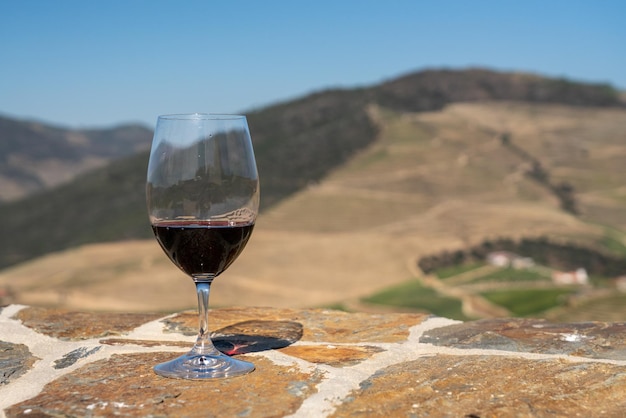 Glass of red wine or port for tasting above the hillsides of the Douro valley in Portugal