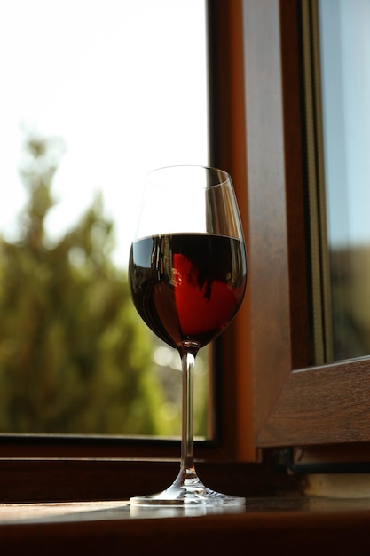 木製の窓辺に赤ワインのグラスが立っています