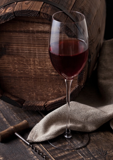 Стакан красного вина и старинный штопор и старый ствол на деревянный стол