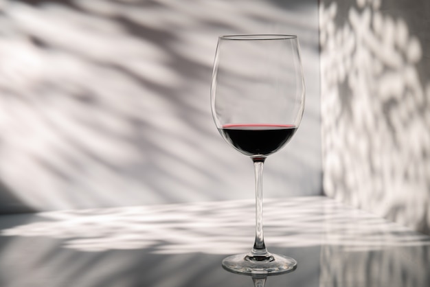 Glass of red wine on a wall space with beautiful light and shadow