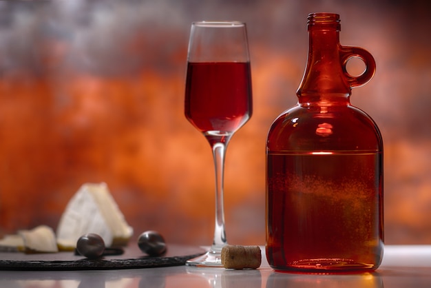 Glass of red wine with bottle and cheese board on a bar or pub counter