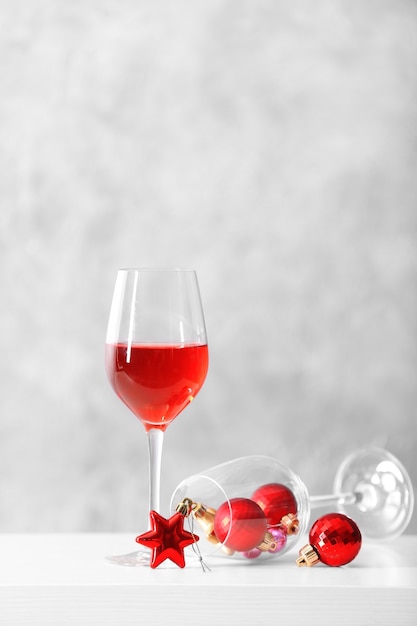 Glass of red wine with christmas accessories on grey wall background