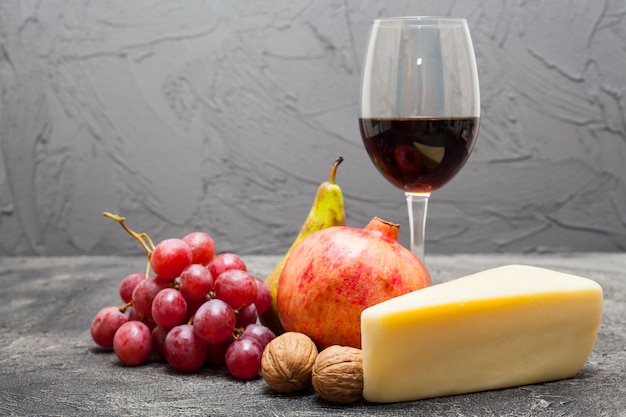 A glass of red wine with grapes and cheese