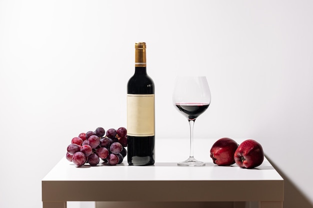 Glass of red wine with grapes on white table