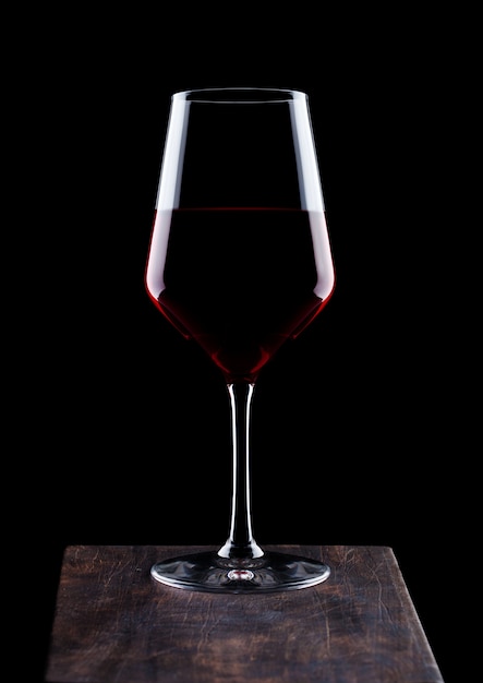 Glass of red wine on wooden board on black background  