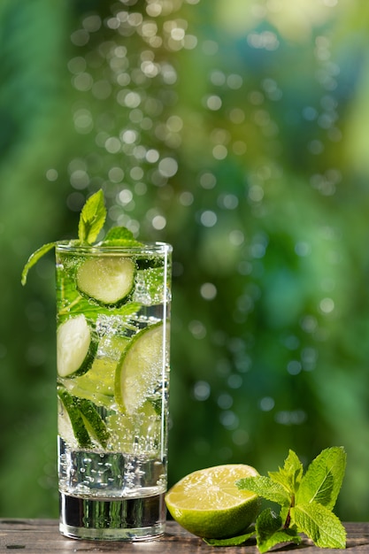 In a glass a refreshing summer drink with cucumber and lime, large gas bubbles