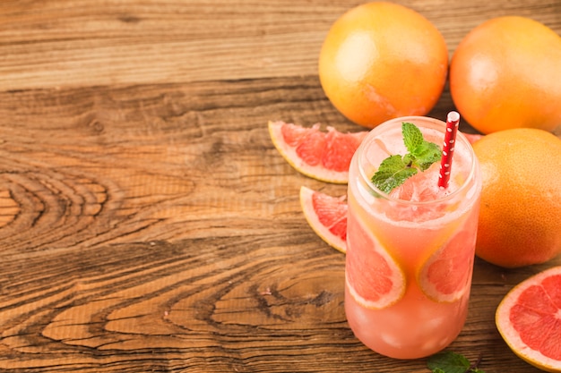 Photo a glass of ripe grapefruit with juice on wooden table close-up