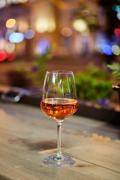 Glass of rose wine on bar counter with night city view