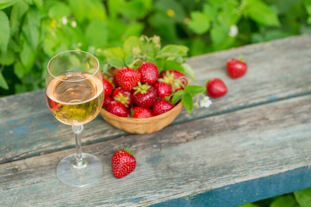 A glass of rose wine served with fresh strawberries on wooden surface