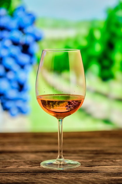 Glass of rose wine with blurred vineyard