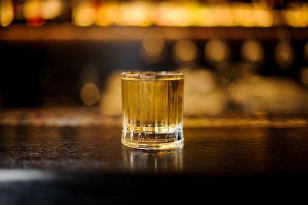 Glass of a Rusty Nail cocktail on the wooden bar counter