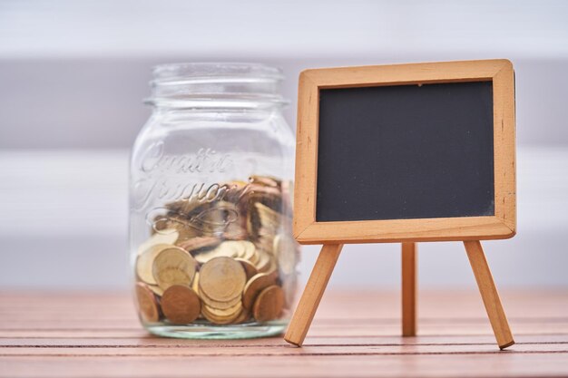 Photo glass saving jars and blank blackboard on wooden table top