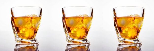 白い背景の上の氷とスコッチウイスキーのガラス