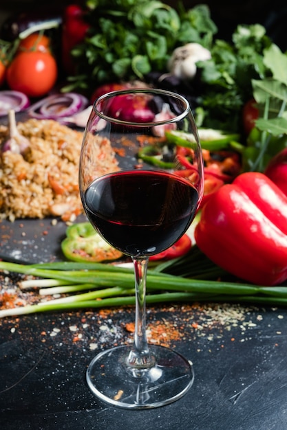 A glass of semisweet or dry red wine on vegetable background.