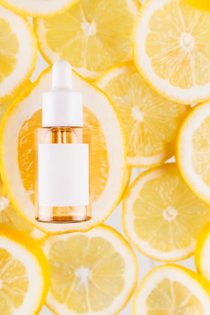 Glass serum bottle with lemon slices zest serum or essential oil concept with lemon