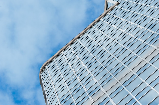 Glass skyscraper building against sky background square