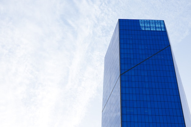 Glass skyscraper building with cloudy blue sky background