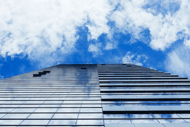 Glass skyscraper building with cloudy blue sky background