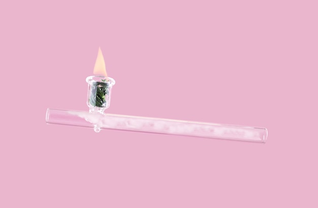 Glass smoking pipe on pastel pink background