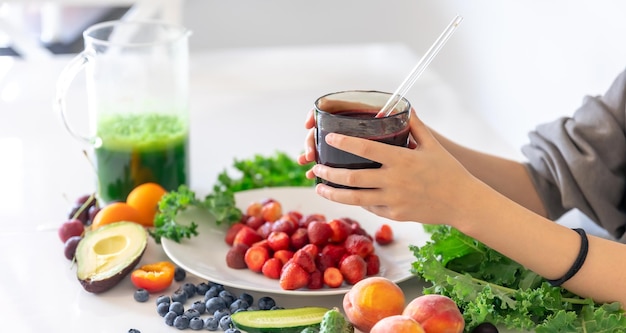 A glass of smoothie from berries in a childs hand at home in the kitchen