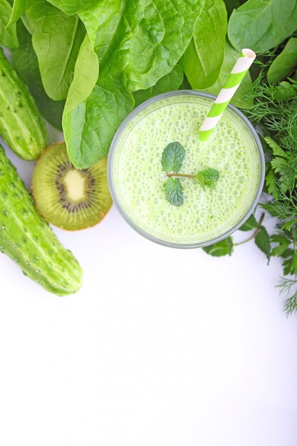 A glass of smoothie with green vegetables and spinach