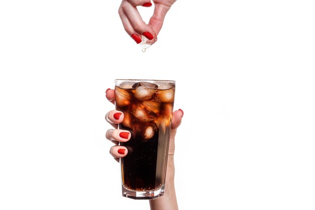 Glass of soda drink with ice in female hand isolated on white background