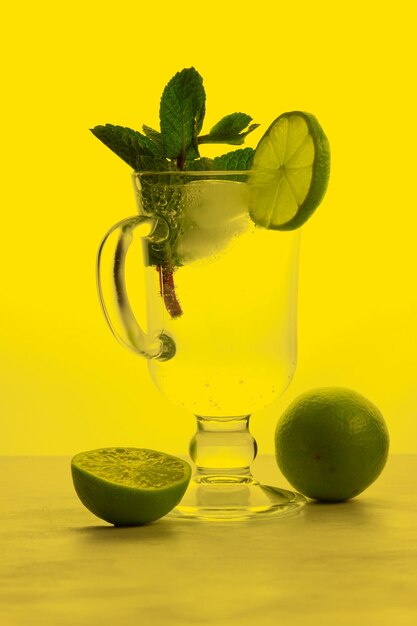 Glass of soda drink with lime slices and mint on a colored background summer cold drink concept closeup