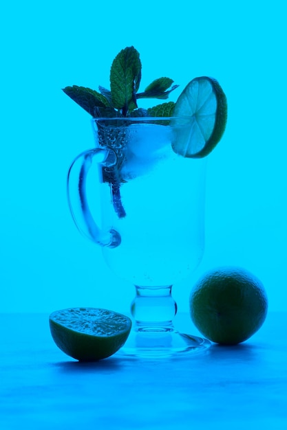 Glass of soda drink with lime slices and mint on a colored background Summer cold drink concept Closeup