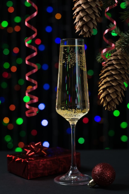 A glass of sparkling wine and a Christmas tree on a bokeh surface