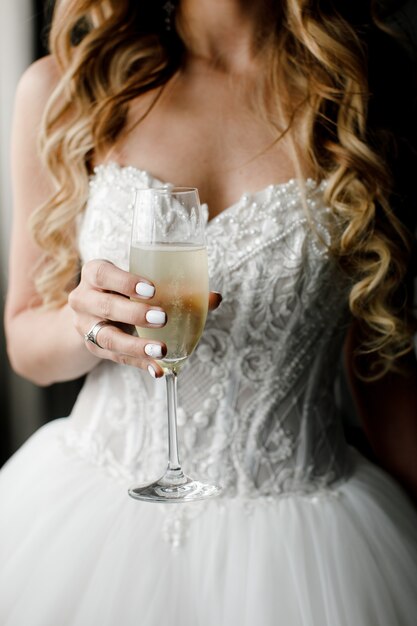 A glass of sparkling wine in the hands of the bride