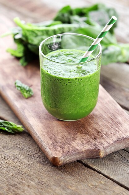 Glass of spinach juice on wooden table closeup