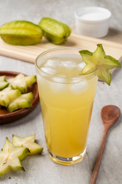 Glass of starfruit juice with ice and fruit slices.