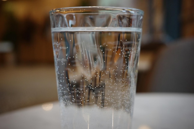 Стакан негазированной воды с пузырьками на столе в кафе крупным планом.